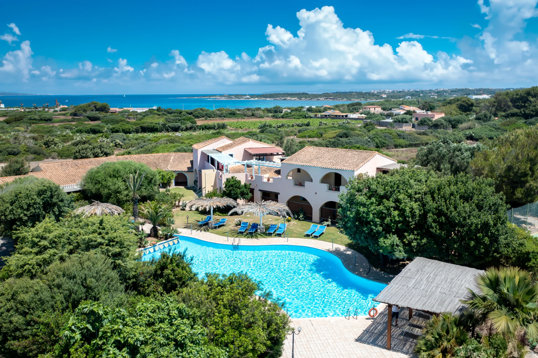 Hotel Luci del Faro con piscina circondata da vegetazione mediterranea e vista sul mare di Calasetta