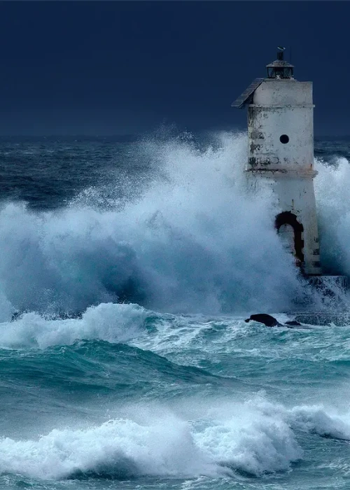 Faro di Mangiabarche a Calasetta con onde che si infrangono durante una tempesta in mare