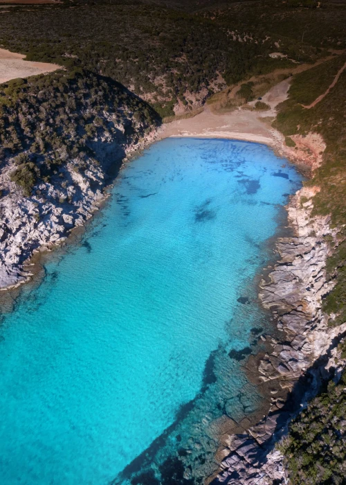 Vista aerea della piscina dell'Hotel Luci del Faro circondata da lettini e ombrelloni con acqua cristallina turchese