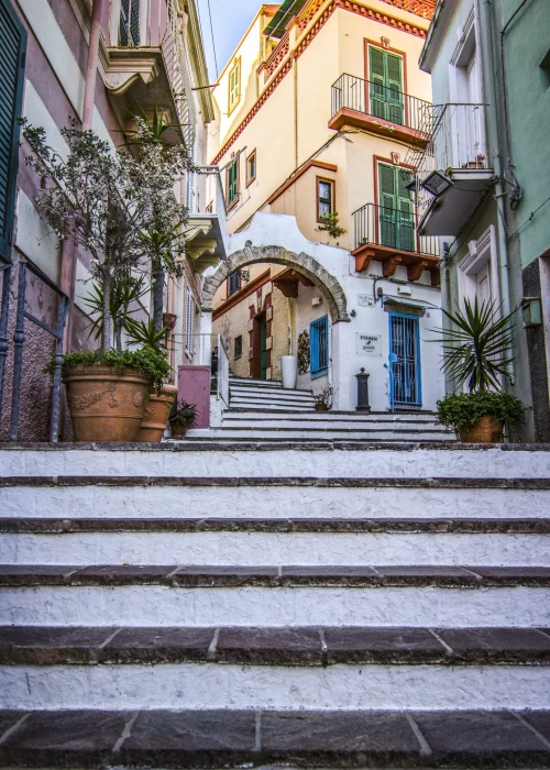 Scalinata in pietra nel centro storico di Calasetta con edifici colorati e piante ornamentali