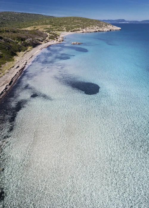 Vista aerea della spiaggia di Calasetta con mare cristallino turchese, sabbia bianca e costa mediterranea sarda