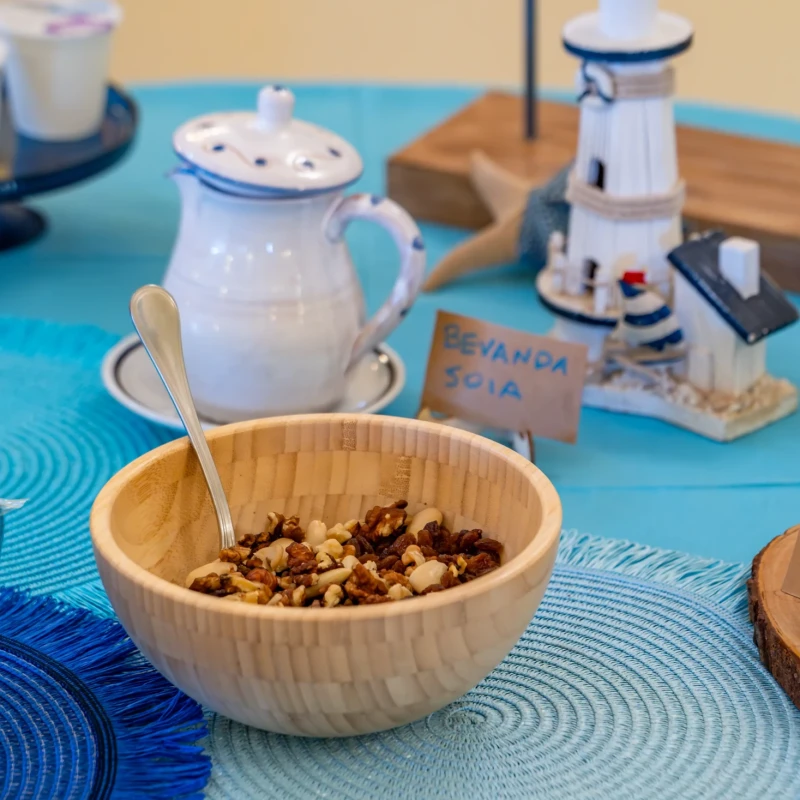Tavola per colazione con ciotola di cereali, caffettiera, decorazioni marinare e piscina dello sfondo