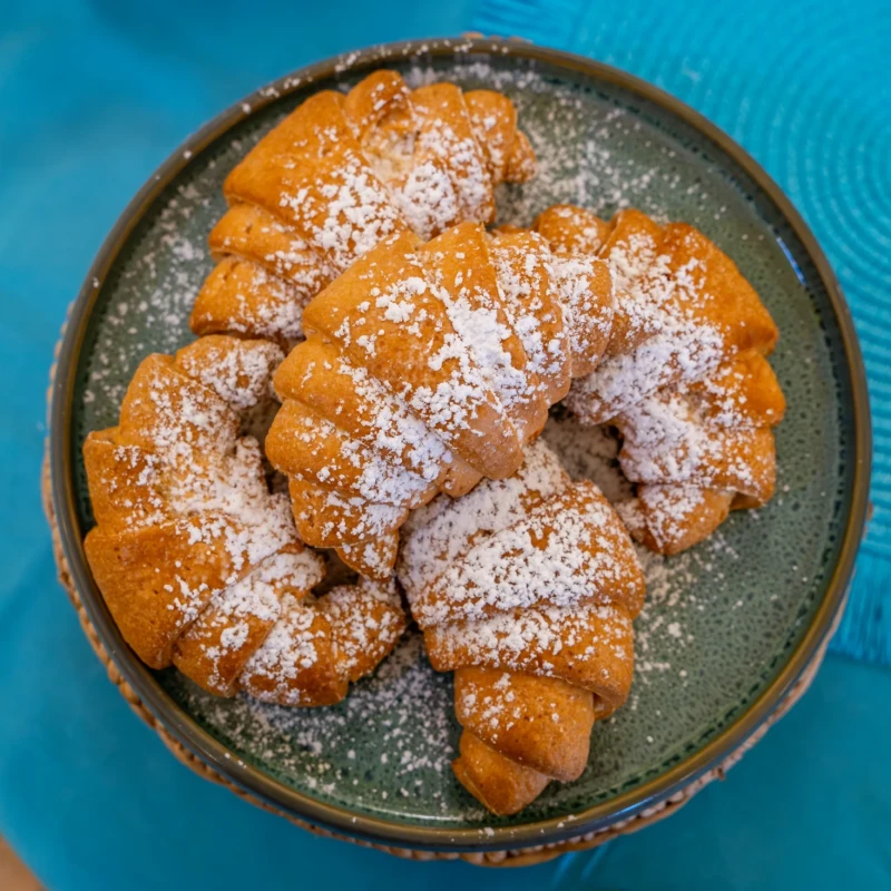 Ciambella dolce spolverata di zucchero a velo servita su piatto ceramica color turchese all'Hotel Luci del Faro