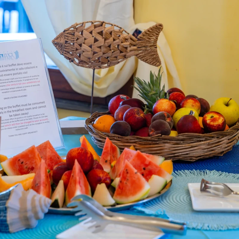 Buffet colazione Hotel Luci del Faro con frutta fresca, anguria, cestini di vimini e decorazione a forma di pesce