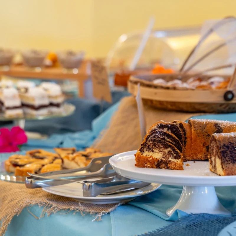 Buffet di dolci e pasticcini su tavolo con tovaglia blu all'Hotel Luci del Faro a Calasetta
