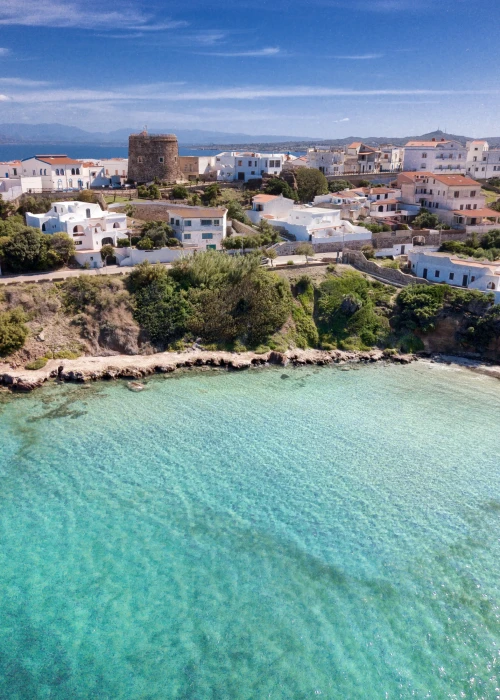 Vista aerea della spiaggia di Calasetta con acque turchesi cristalline e case colorate sul lungomare