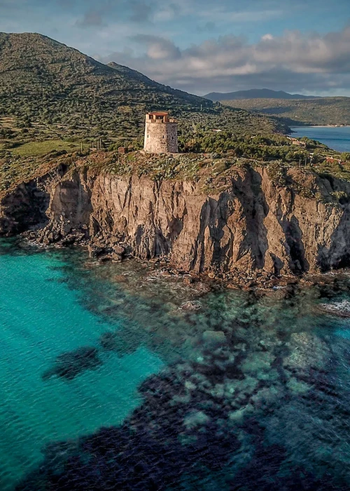 Torre spagnola su promontorio roccioso circondata da mare turchese cristallino a Calasetta, Sardegna